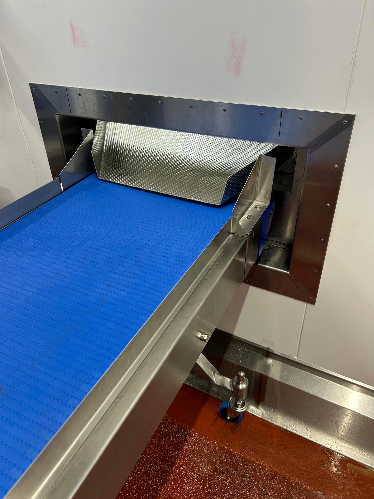 Stainless conveyor entering a production opening