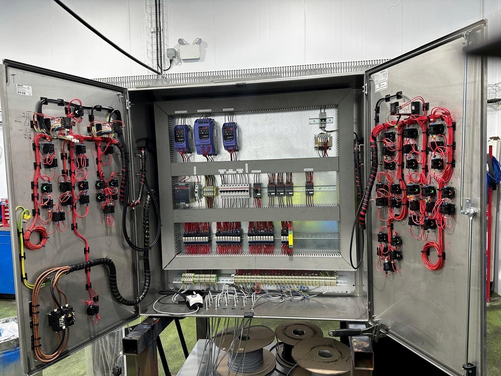 Large industrial electrical control cabinet with neatly routed wiring and automation components